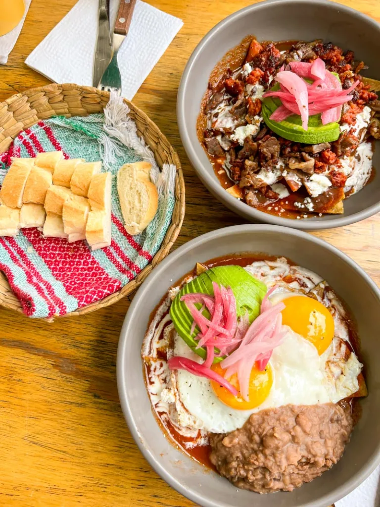 Two bows of chilaquiles and a bread basket at romaquil, a top place when looking for where to eat in Roma Norte, mexico city.