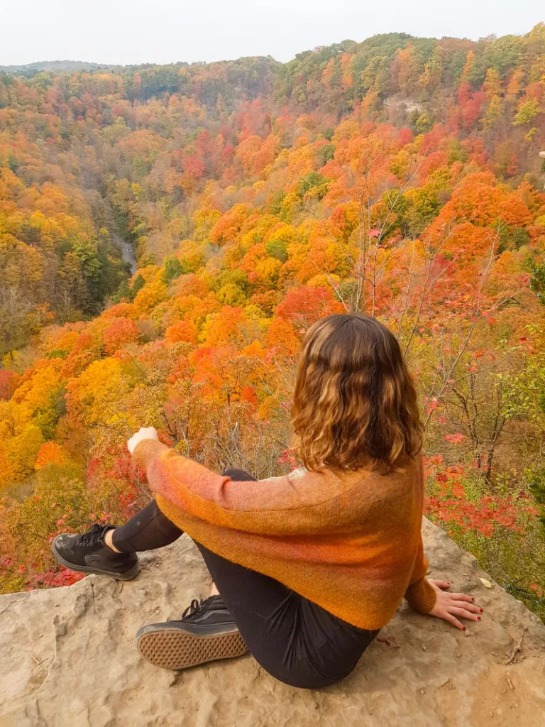 Woman sitting at Dundas Peak, the best place to see fall colors near toronto