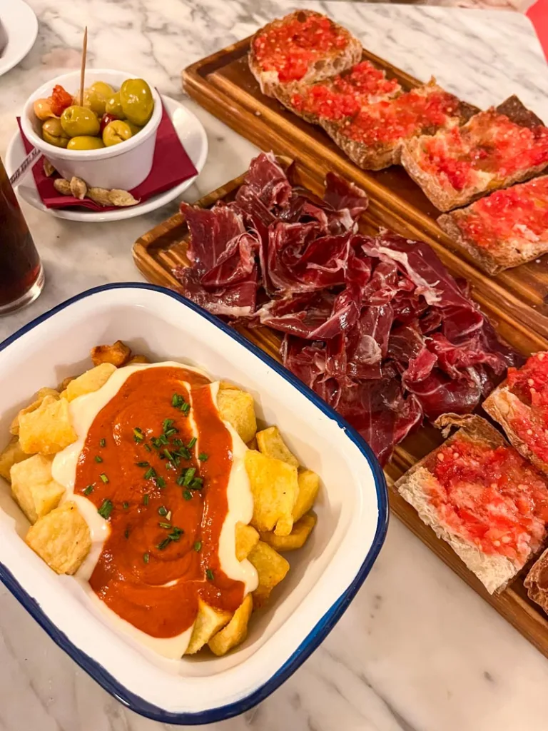 tapas plates at bodega vasconia in barcelona: patatas bravas, a jamon plate, and pan con tomate