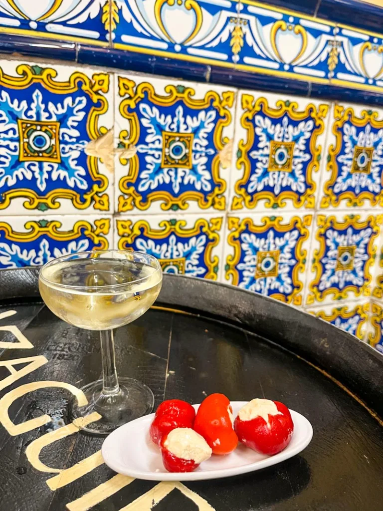 a glass of cava and a plate with cream chesse stuffed peppers at el xampanyet in barcelona