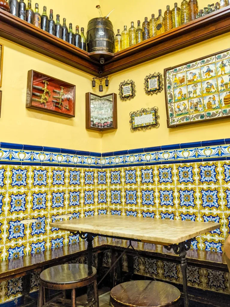 traditional yellow and blue tiled walls inside El Xampanyet in Barcelona