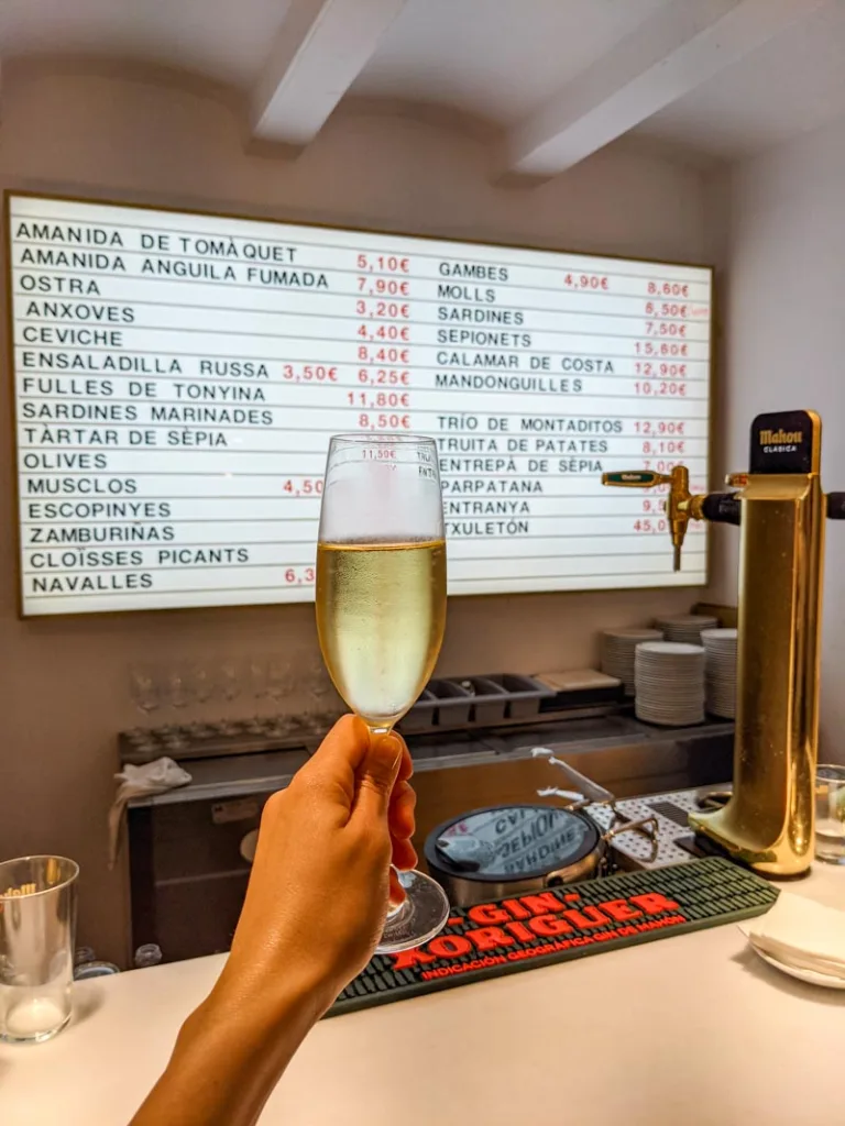 hand holding a cava glass infront of the minimalist menu at lluritu  in barcelona
