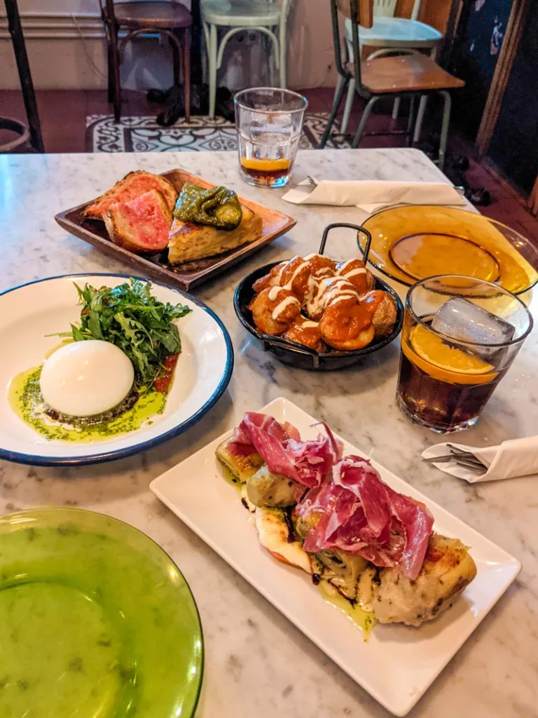 various tapas plates at palosanto in barcelona: artichokes with jamon iberico, mozarella, patatas bravas, spanish tortilla and pan con tomate