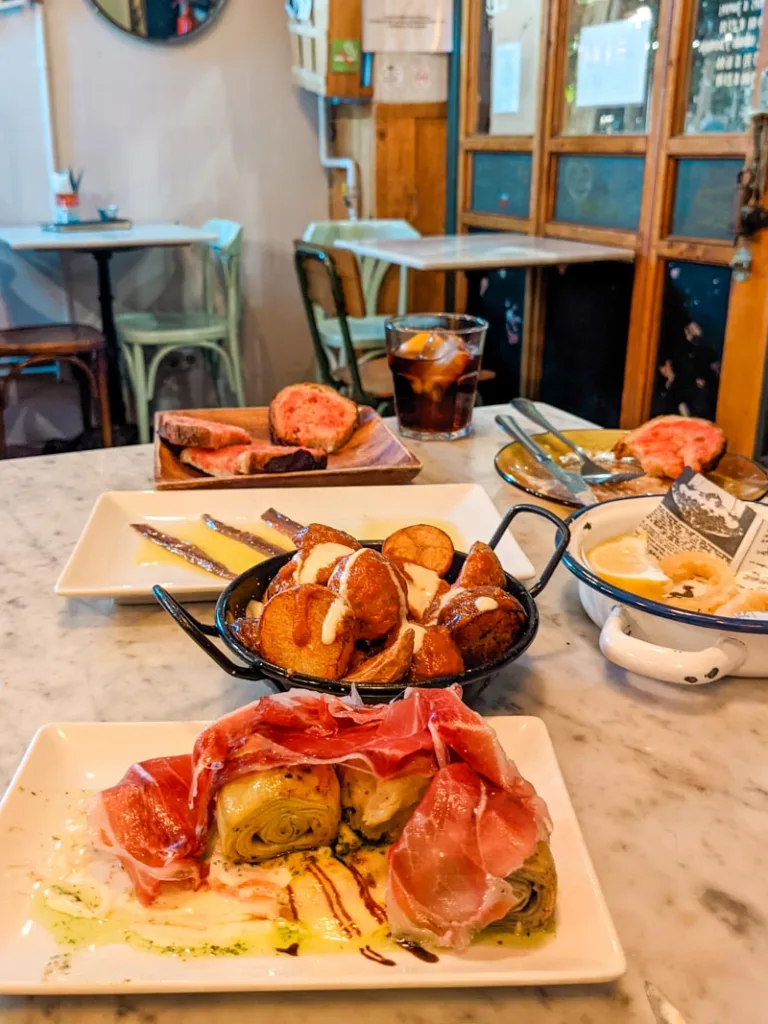 tapas plates at palosanto resturant in barcelona: artichokes with jamon iberico, anchovies, patatas bravas, spanish tortilla and pan con tomate
