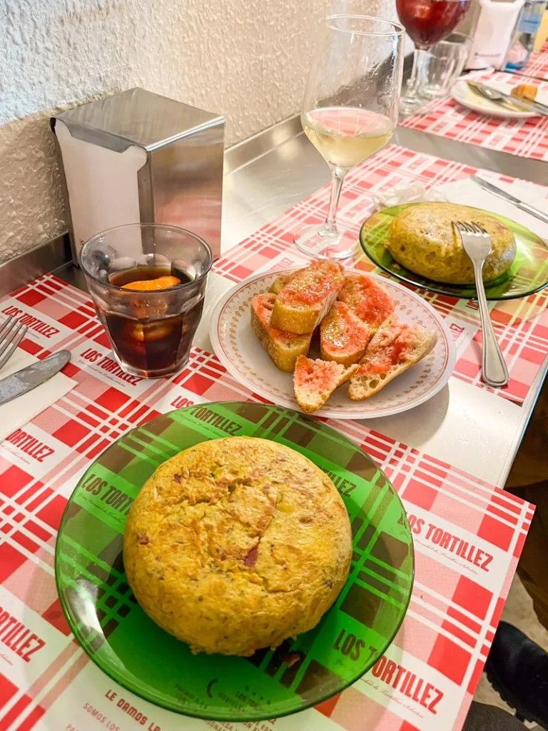 Two full round tortillas de patatas and a plate of pan con tomate at a restaurant in barcelona