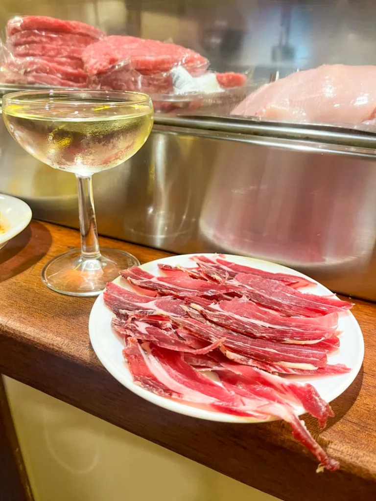 big plate of jamon iberico and a glass of cava on a wooden bar in barcelona