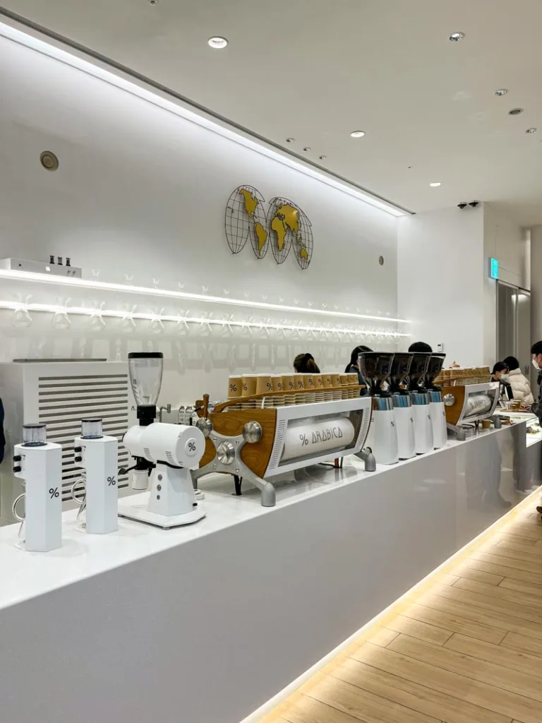 minimalist interior of %arabica in seoul with white walls and gold details