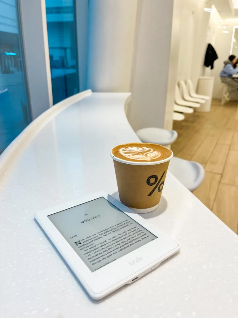 a latte on a white bar, next to a kindle at %arabica coffee shop in seoul