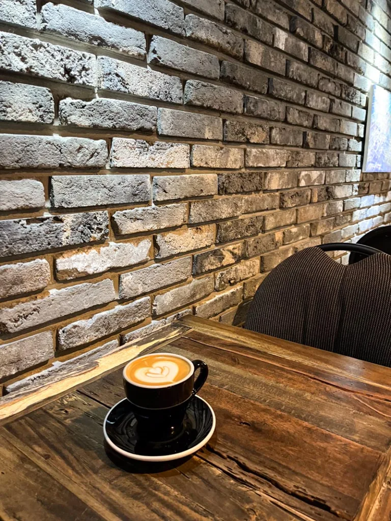 capuccino on a wooden table, against a brick wall inside astronomers coffee in seoul