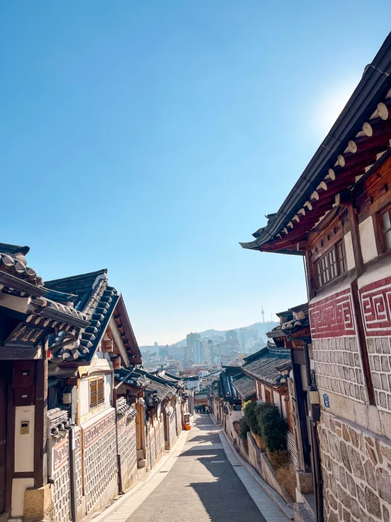 street view of the bukchon hanok village houses with a faint shape of the n-seoul tower in the background