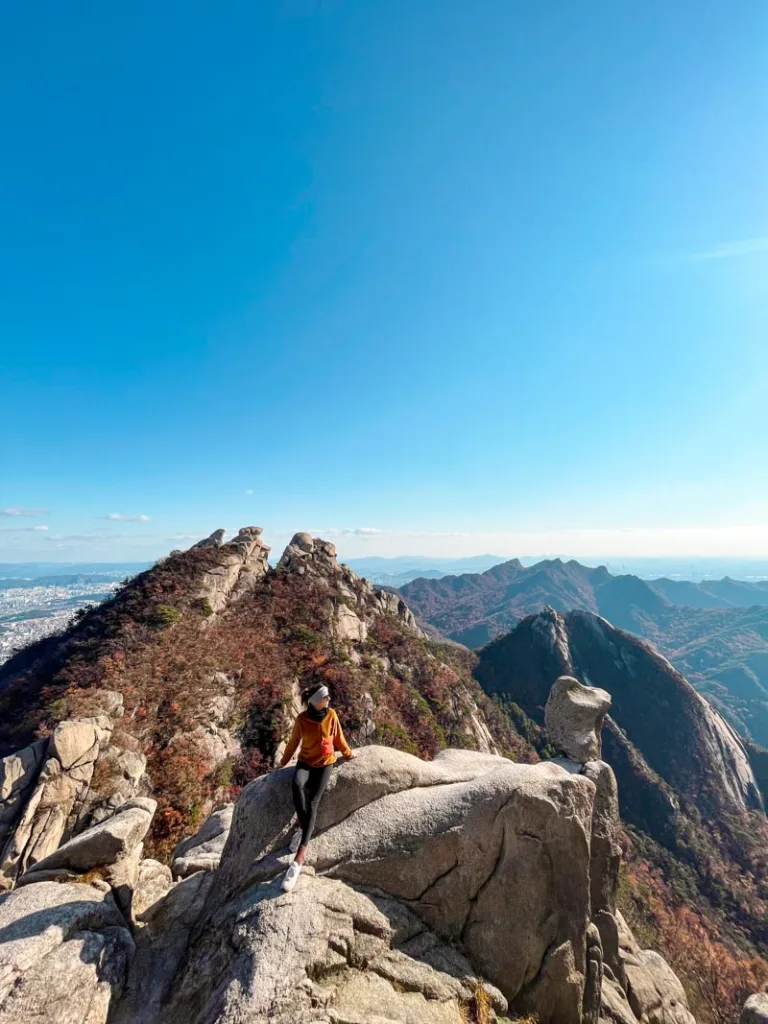 woman sitting on a rock at the peak of the bukhansan national park in seoul