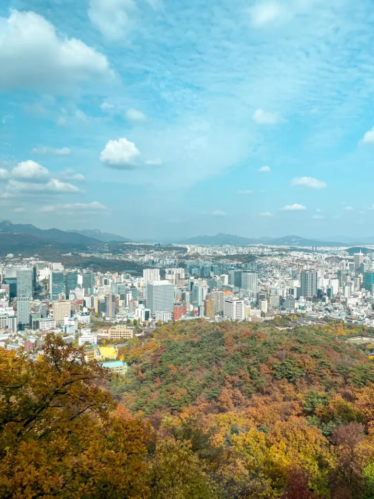 view from a cable car of fall foliage and seoul city at the back