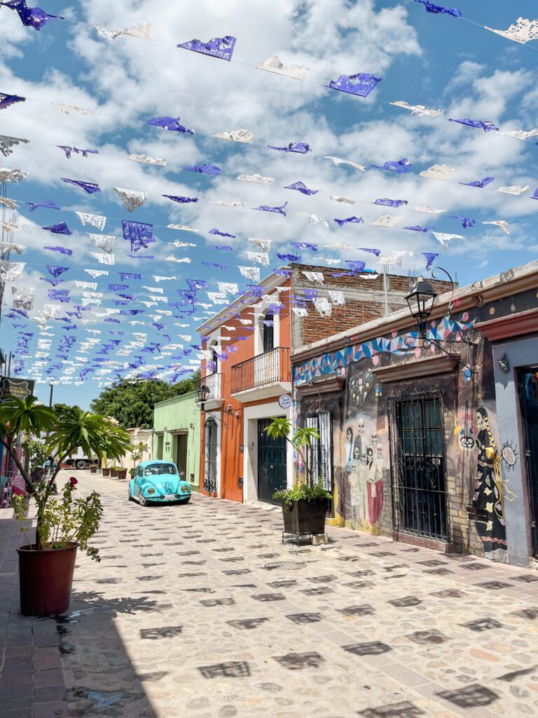 Colorful streets of jalatlalco in Oaxaca City with houses decorated with murals and papel picado dangling over the residential street