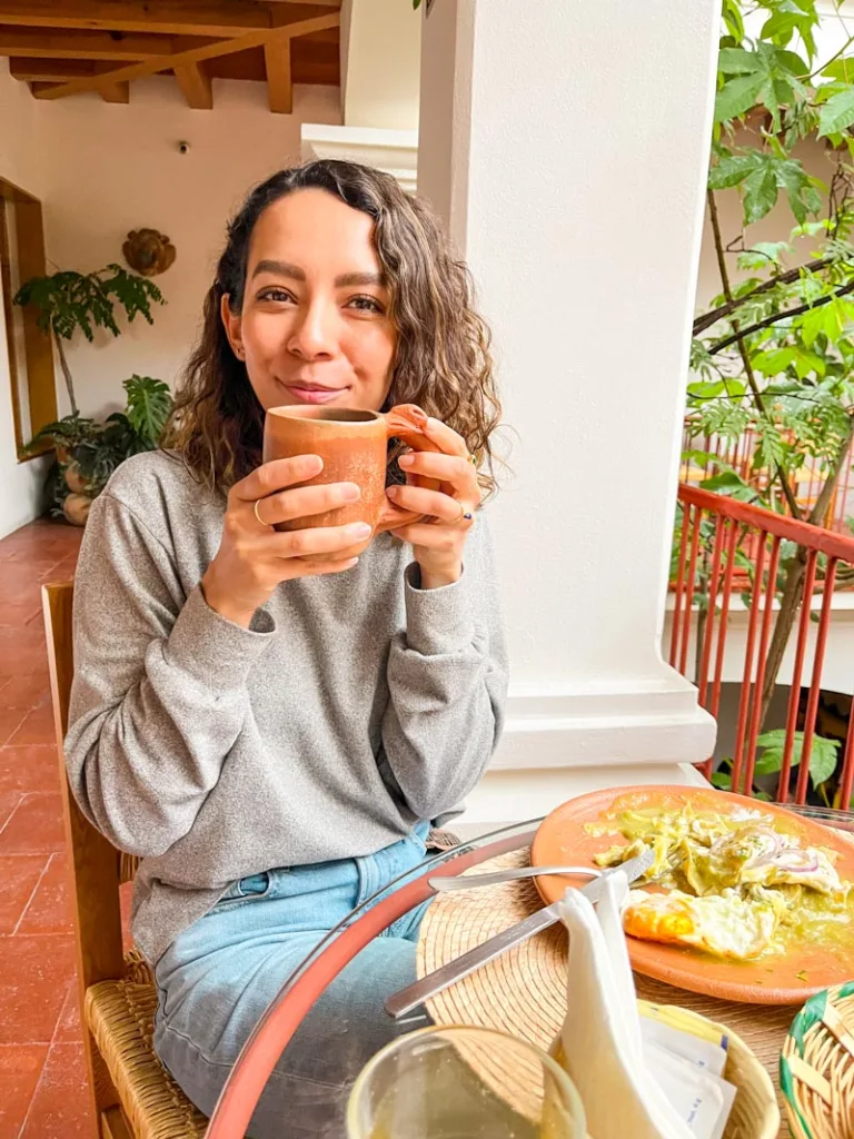 woman holding a coffee cup at the breakfast table at a hotel in oaxaca city