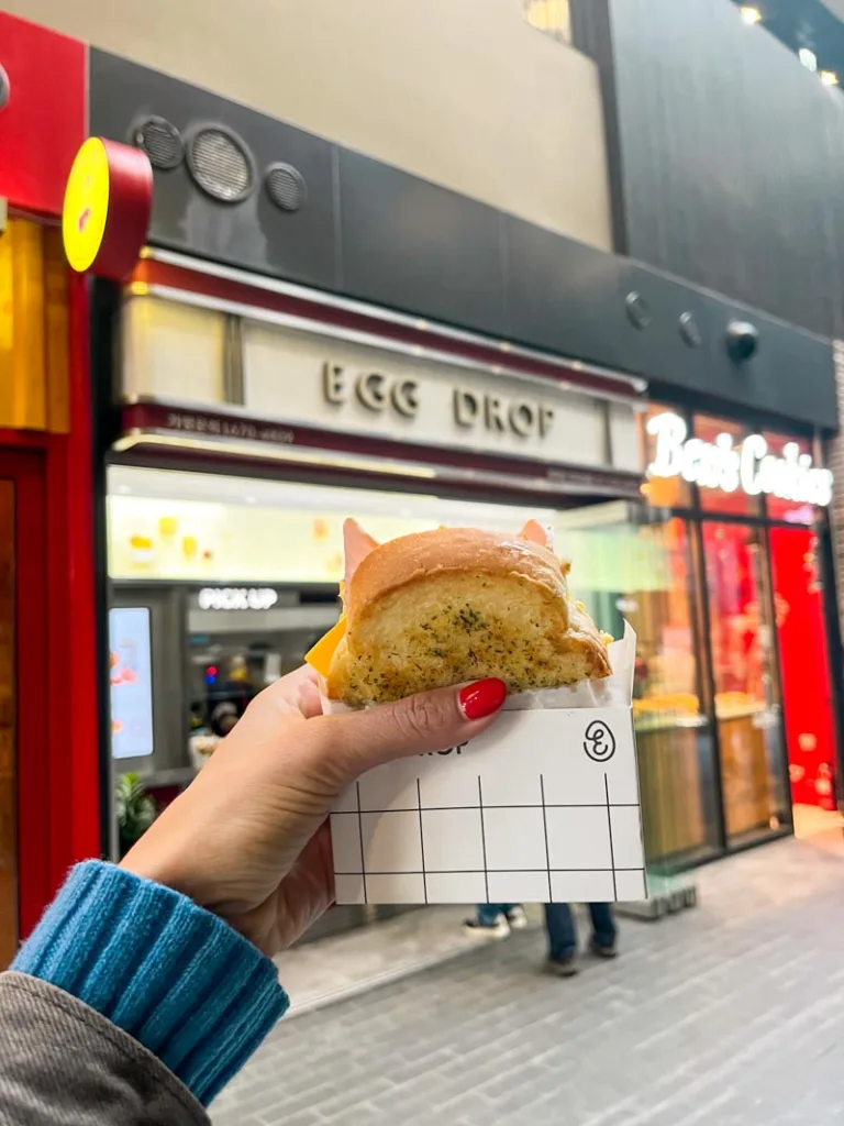 hand holding a fluffy korean egg sandiwch to go from egg drop in seoul