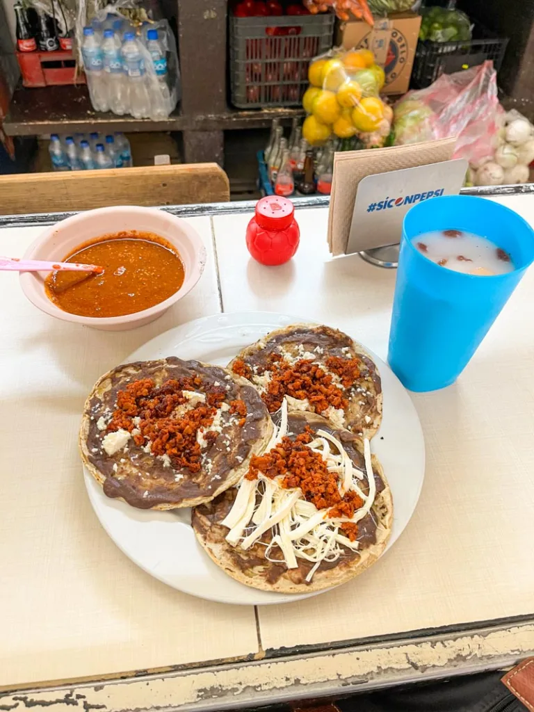 plate with three memelas with beans, cheese and chorizo at a food market in oaxaca city
