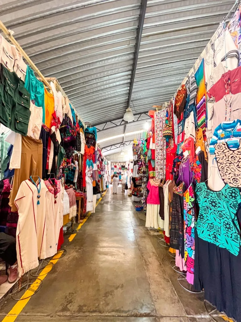 alley of an indoor market lined with colorful textiles at mercado de artesanias in oaxaca city
