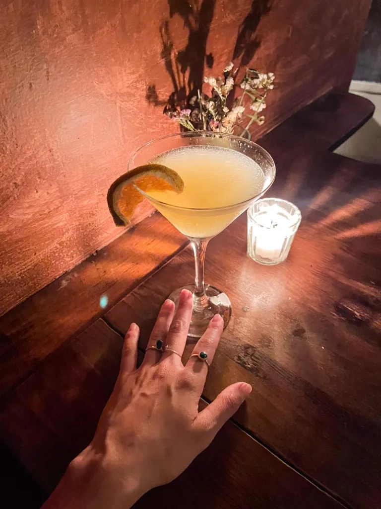 hand holding a cocktail served in a martini glass at mezcalogia in oaxaca city