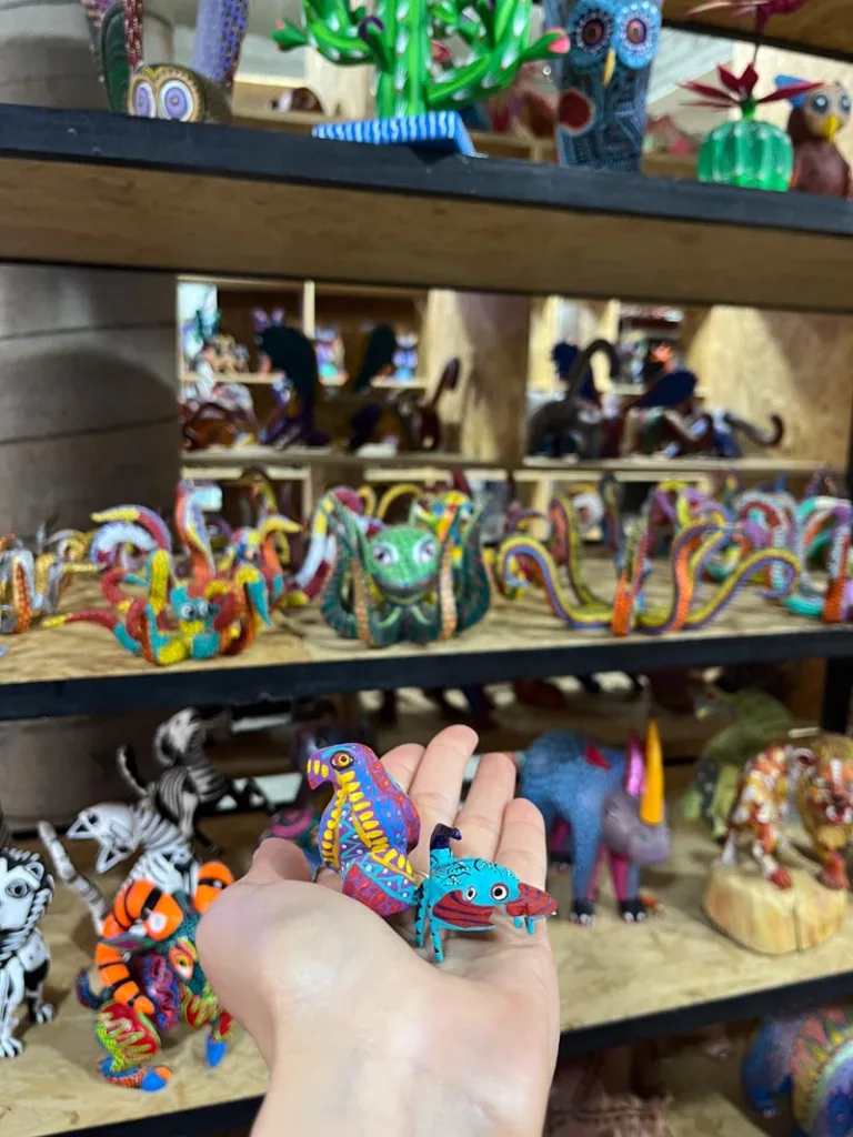 hand holding a colorful alebrije, a small wood figure from a oaxacan workshop
