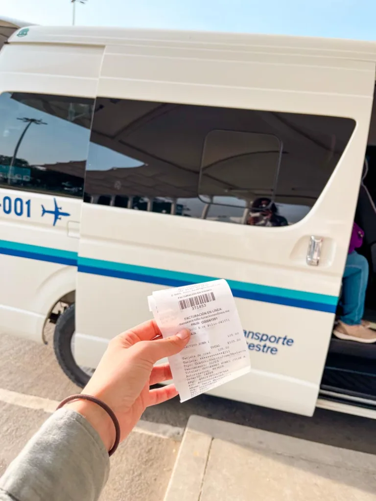 Hand holding a ticket for the collective shuttle bus at the Oaxaca City airport