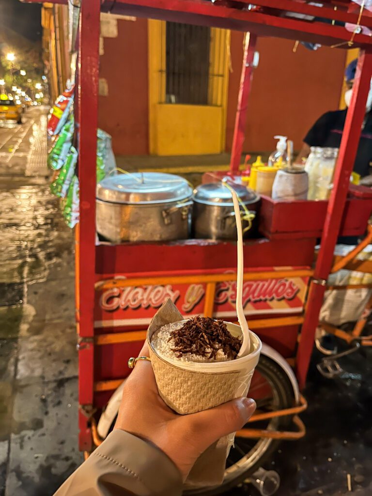 Hand holding corn in a cup, a Mexican street food dish, in Oaxaca City
