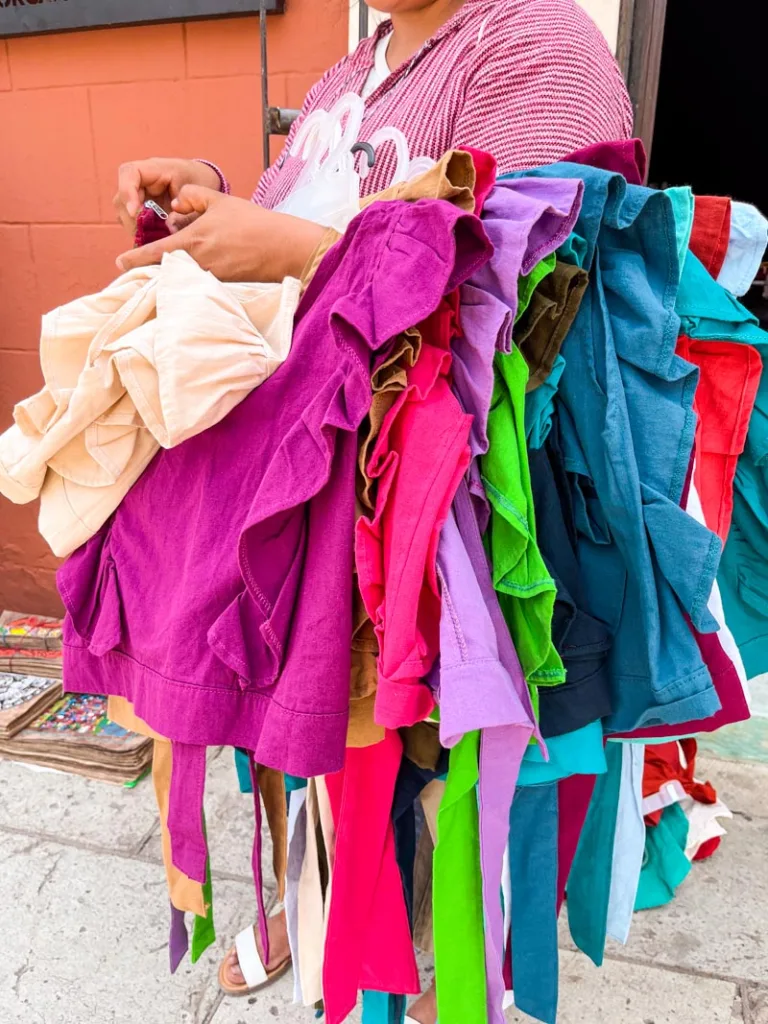 street seller carrying around lots of colorful cotton tops in oaxaca city