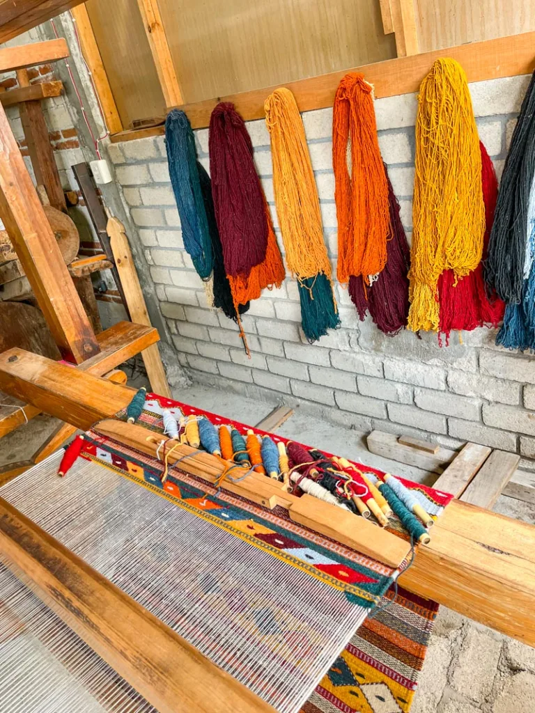 colorful yarn hanging above a weaving machine in a workshop in oaxaca city