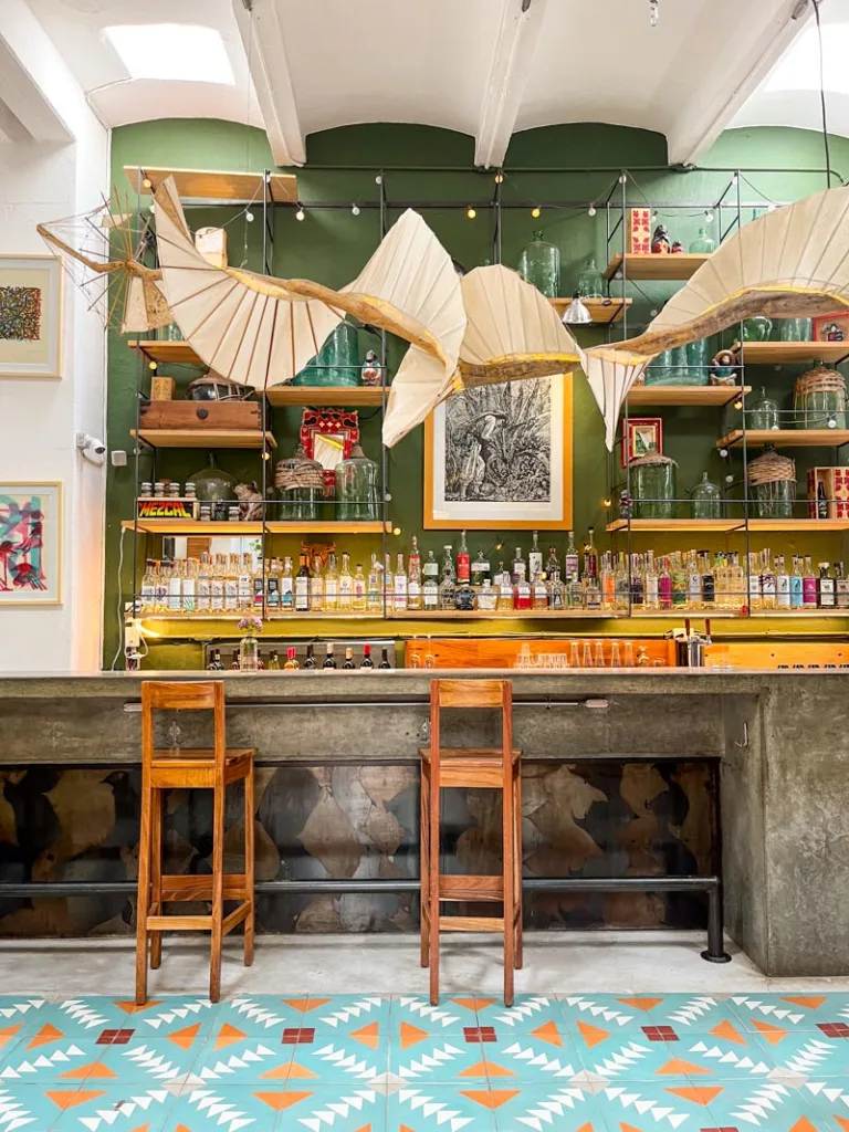 contemporary bar with blue tile floor, wooden bar stools, and green wall, at zandunga sabor istmeño in oaxaca city