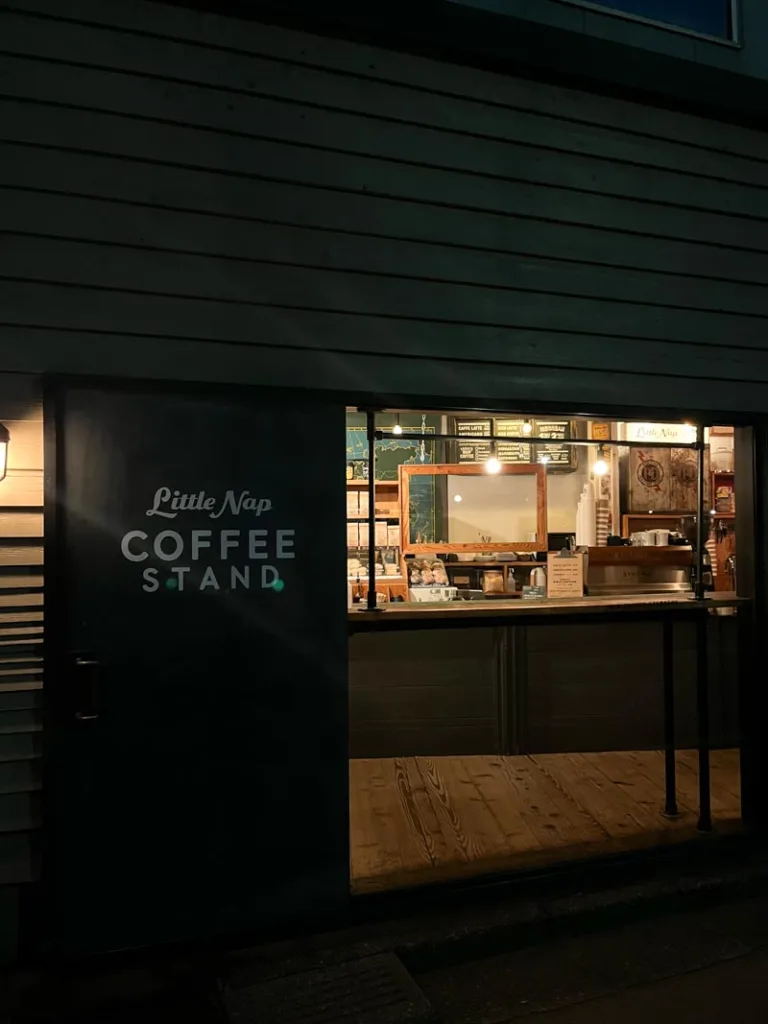 black wooden facade of little nap coffee shop in tokyo, and the lit up interior being seen through a glass wall