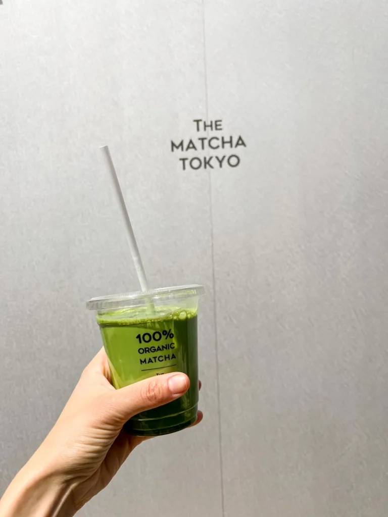 Hand holding an iced matcha latte outside Matcha Tokyo