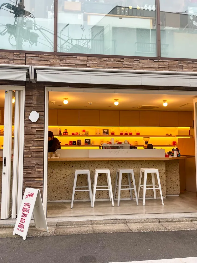 small open coffee shop with a bar with four white metal stools at supreme coffee shop in tokyo