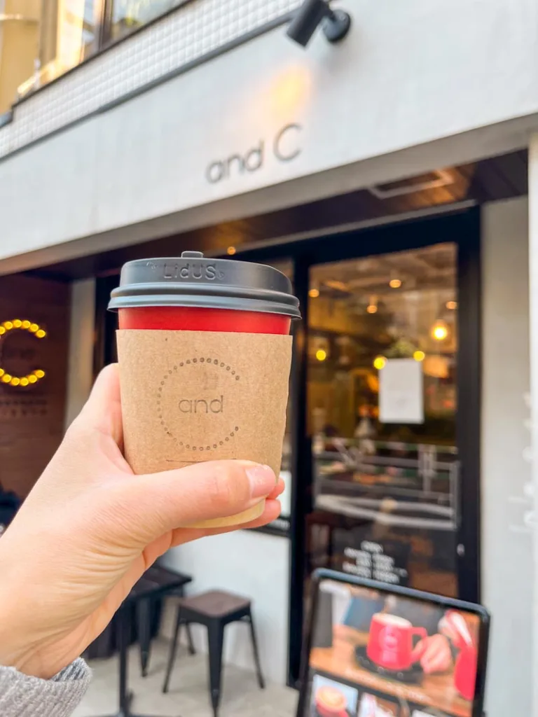 hand holding a to-go coffee cup at and c coffee shop in tokyo