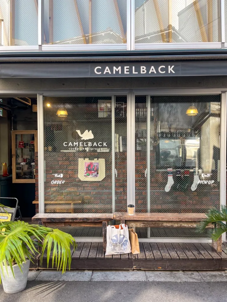 facade of camelback coffee shop with a bench outside and a tote bag in front of it in tokyo