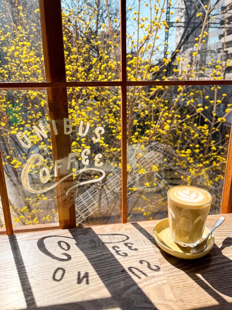 latte on wooden bar next to a window overlooking the train tracks at onibus coffee shop in tokyo