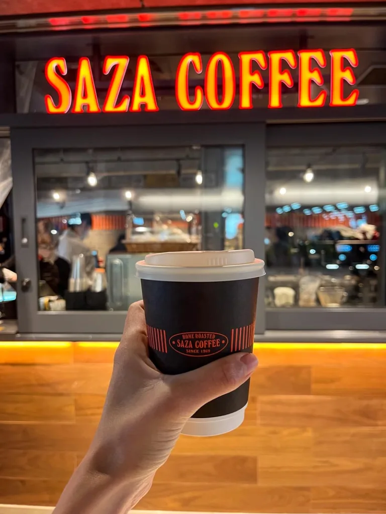 hand holding a to-go coffee cup at saza coffee shop in tokyo's shimbashi station