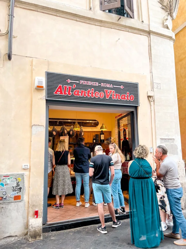 facade of all antico vinaio panino shop in rome with a line of customers outside