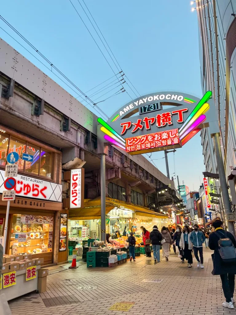 neon sign reading "Ameyokocho" over a busy market street in tokyo