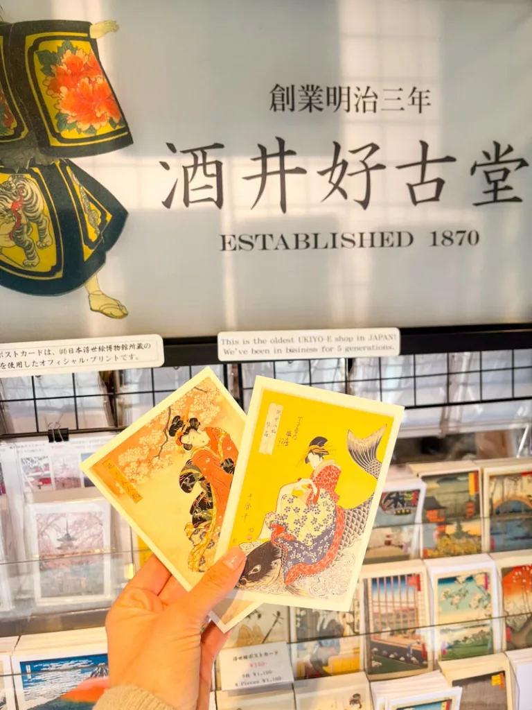 hand holding vintage japanese art style postcards at a shop in nakamise shopping street