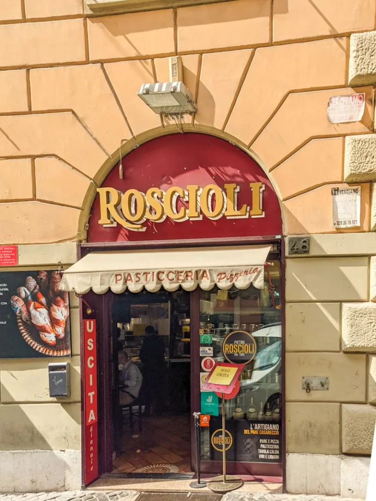 red facade of roscioli bakery with yellow letters in esquilino, rome