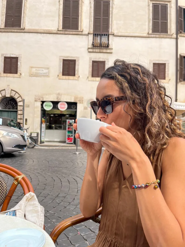 woman sipping on a cappuccino on an outdoor table at caffe sant eustacchio in rome