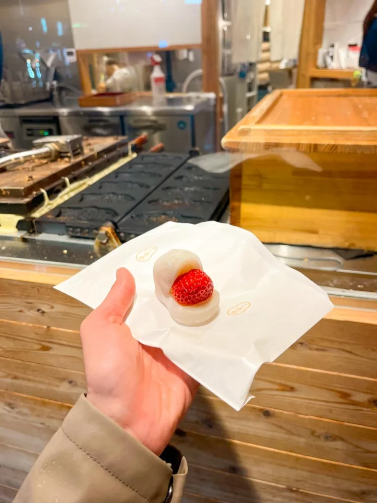 hand holding a strawberry daifuku from a shop in shimbashi, tokyo