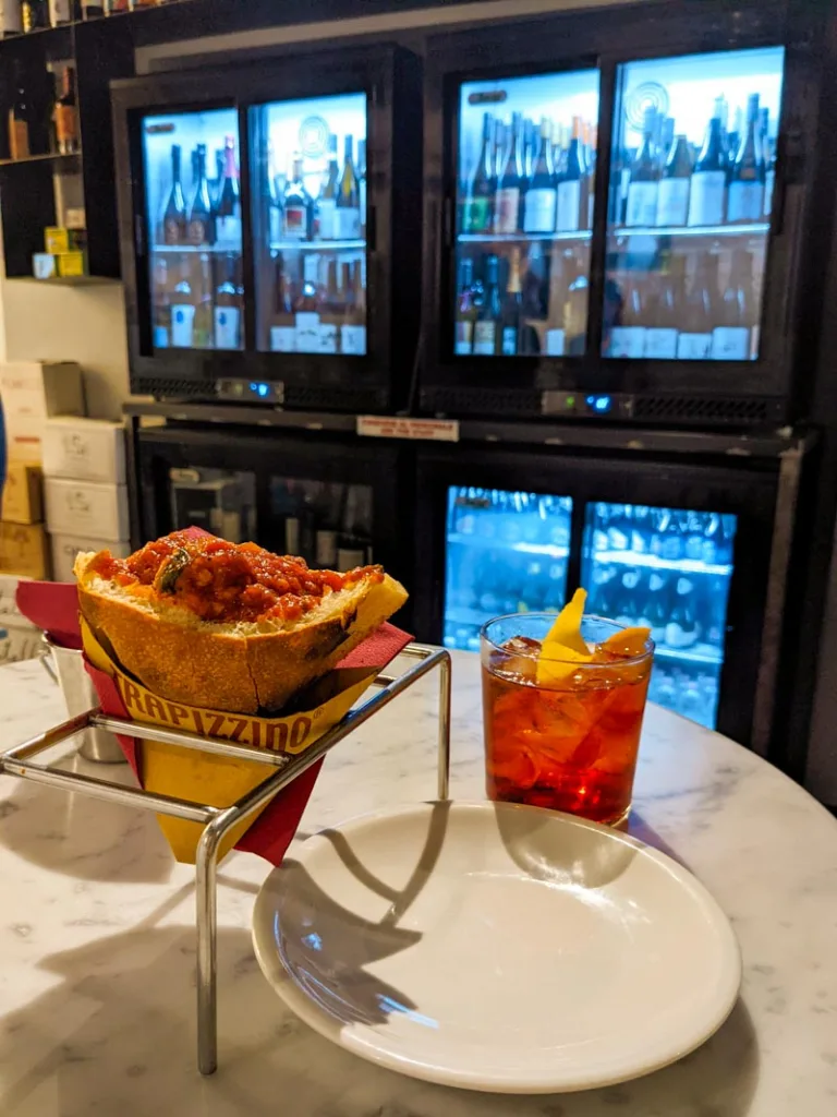 a meatball trapizzino and a negroni on a table at trapizzino in trastevere, rome