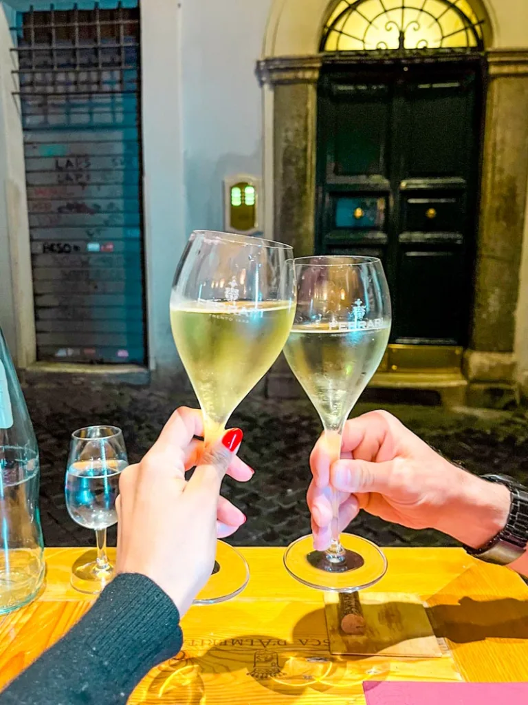 two hands cheering a glass of prosecco at an enoteca in rome