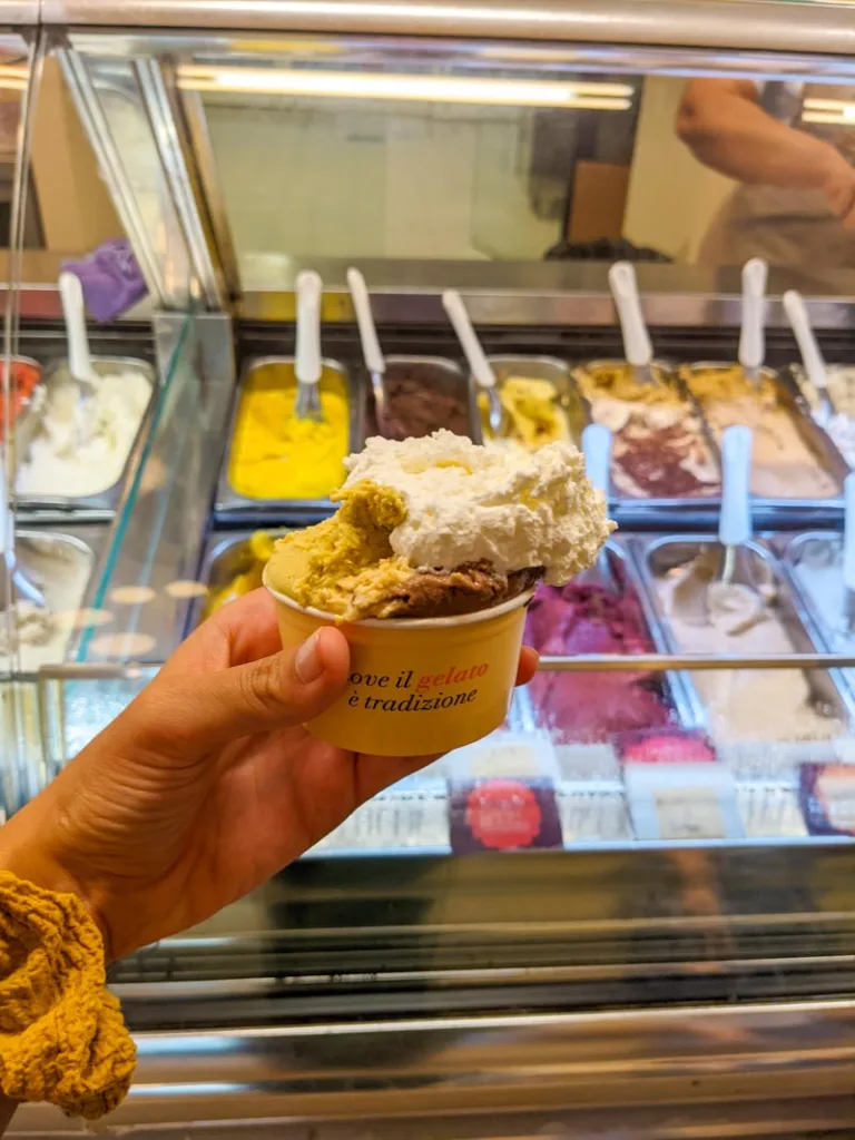 hand holding a gelato cup with cream on top at gelateria fassi in rome