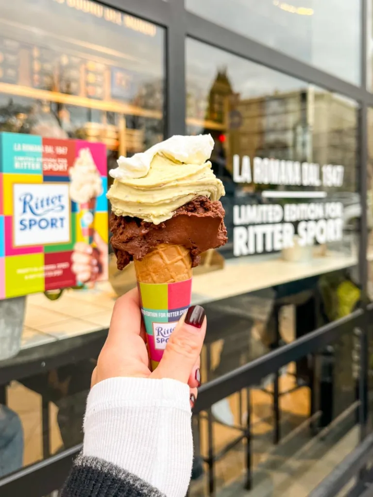 hand holding a gelato cone with whipped cream on top at gelateria la romana in rome