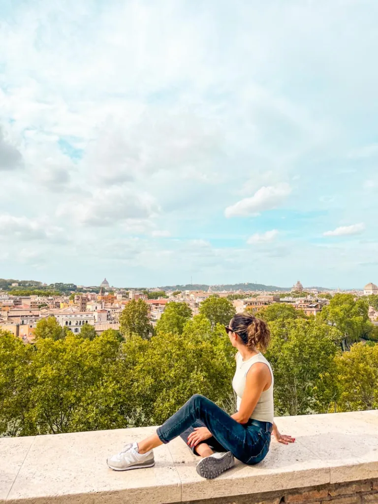 woman sitting on top of a viewpoint at Giardino degli Aranci in rome overlooking the city