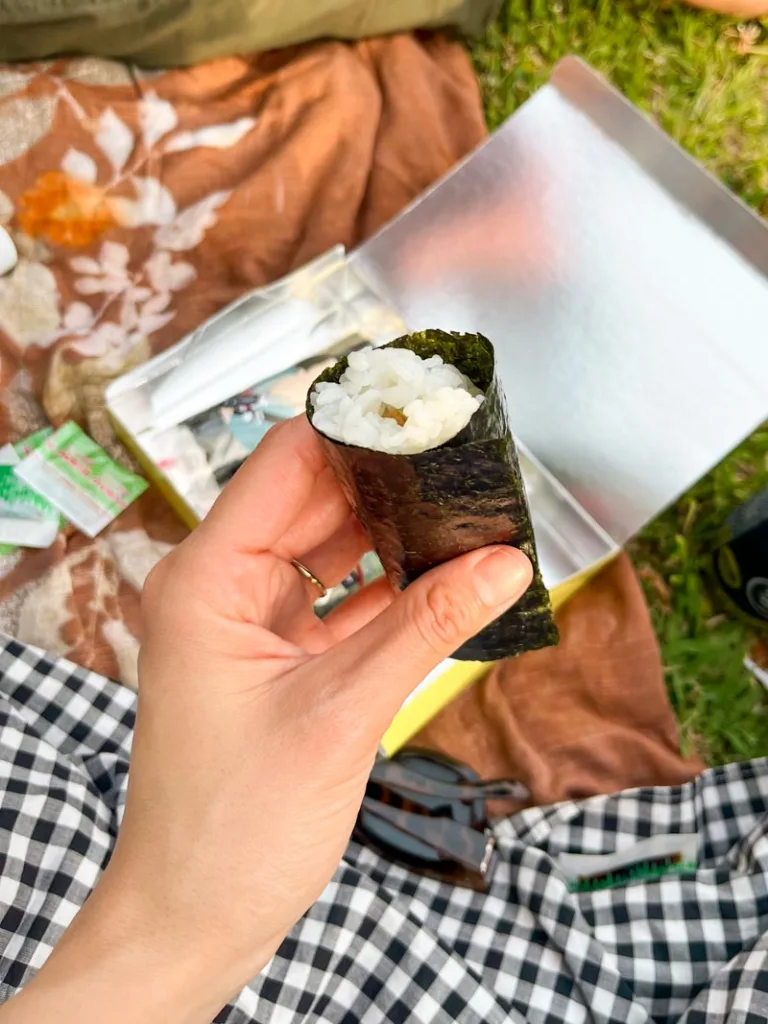 hand holding a tuna roll at a picnic in yoyogi park