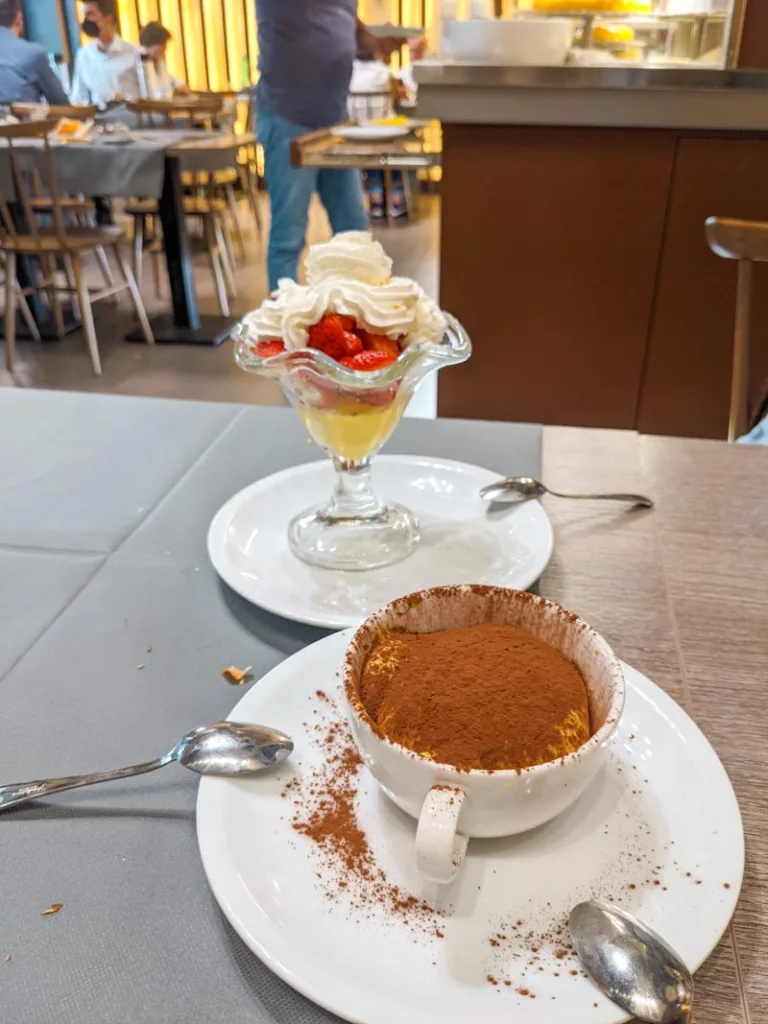 a cup of tiramisu and a bowl of strawberries and cream at la famiglia restaurant in rome