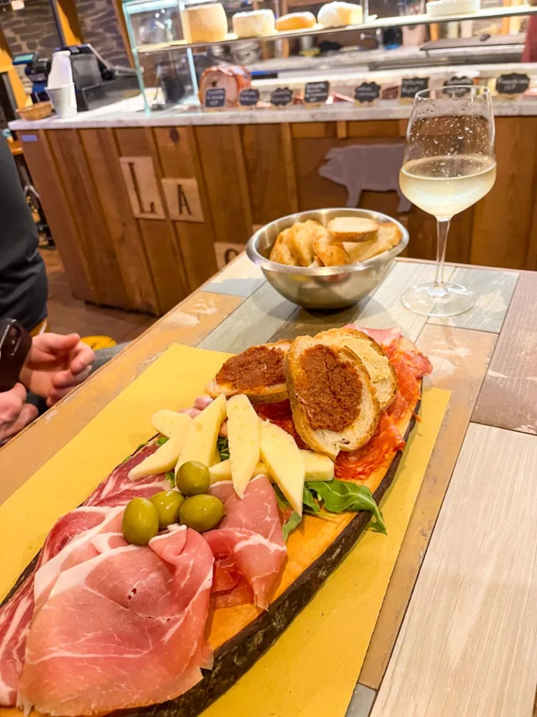 a charcuterie board on a table at la salumeria in rome with a glass of prosecco on the side