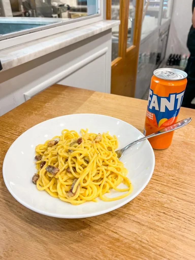 a bowl of carbonara pasta and a fanta at Pastasciutta in rome